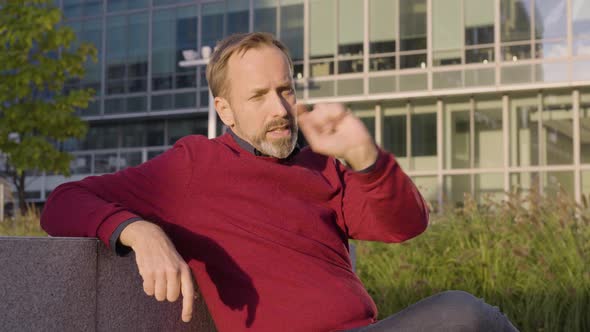 A Middleaged Handsome Caucasian Man Talks to the Camera and Gesticulates As He Sits