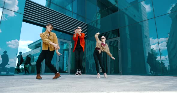 Group of Three Young Dancing People Actively Moving Together, Waving Their Hands, Modern