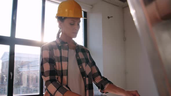 Woman in Helmet with Blueprint at New Home