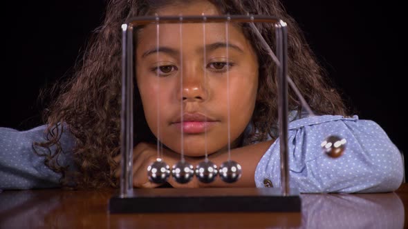 Girl Playing With A Newton's Cradle