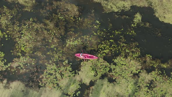 Woman is floating in boat on vacation, drone top view. Female tourist is exploring river in kayak.