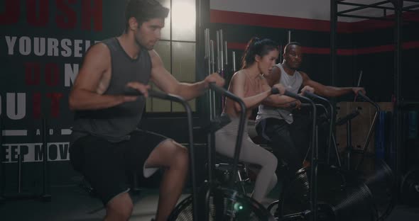 group fit during cardio cycling on air bike cross training at gym