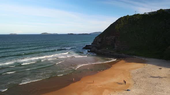 Beautiful golden sand beach with people and cliff side in Buzios, Brazil
