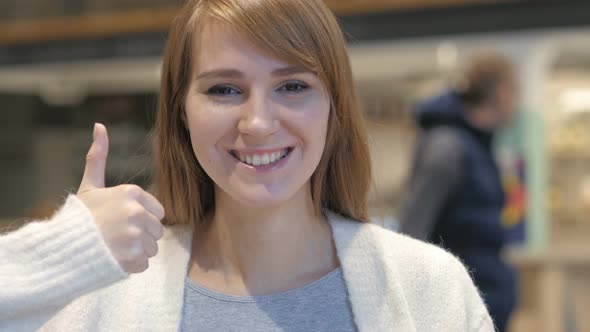 Thumbs Up by Young Woman in Cafe