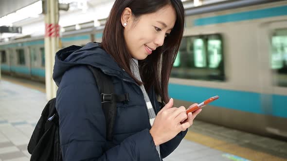 Woman using cellphone at subway station