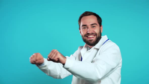 Young Doc Man in Professional White Coat Is Isolated on Blue Studio Background