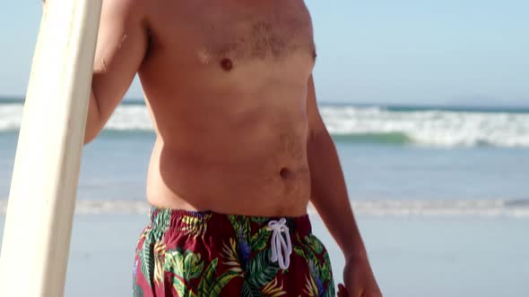 Young man holding surfboard at beach