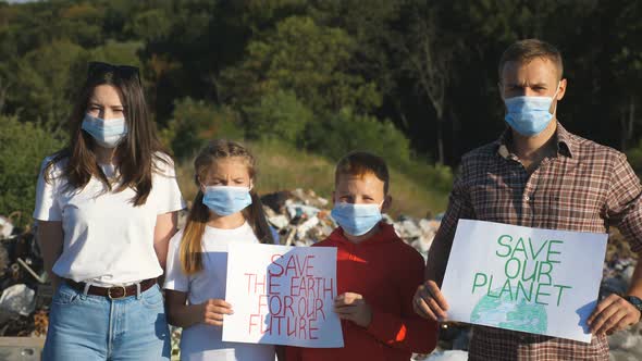 Young Couple with Two Children in Medical Protective Masks Standing Against the Background of