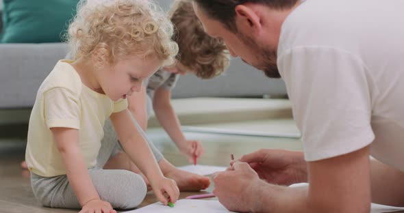 Close Up of a Little Girl and Her Father Who are Drawing on the Floor Girl is Looking at Her Father