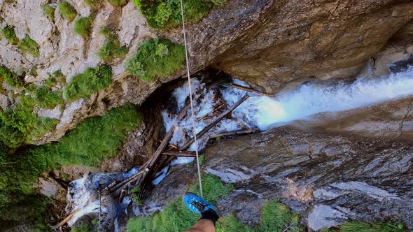 A man walking on a cable that goes across a waterfall. You can not see any security line so it seems