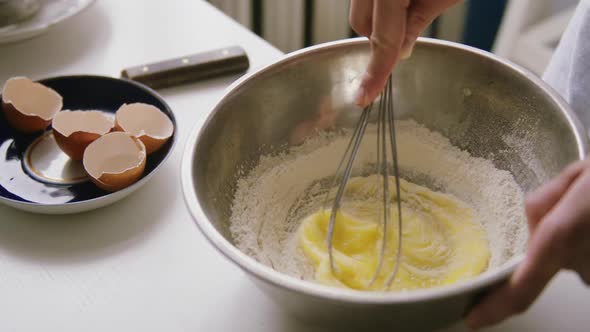 Person Preparing Homemade Omelette Mixing Eggs with Hand Corolla.