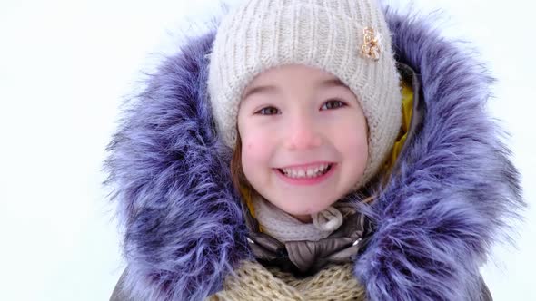 Portrait of a cheerful and happy 5-year-old girl in close-up in winter warm clothes