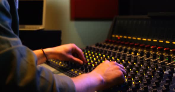 Male audio engineer listening to headphones while mixing sound