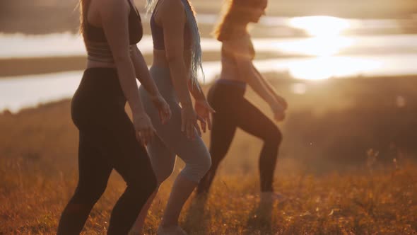 Three Young Women Doing Aerobic Exercises on Sunset Outdoors - Doing Lunges