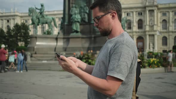 Man is Using Smartphone Standing on Square in Vienna