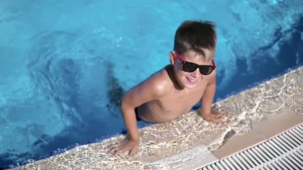 Portrait Baby Boy in Trendy Sunglasses Playing Splash Water at Swimming Pool Summer Vacation Slowmo