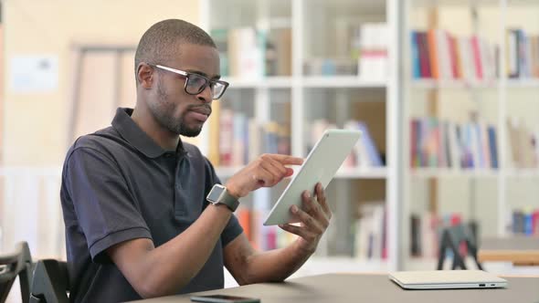 Professional Young African Man Using Tablet in Library