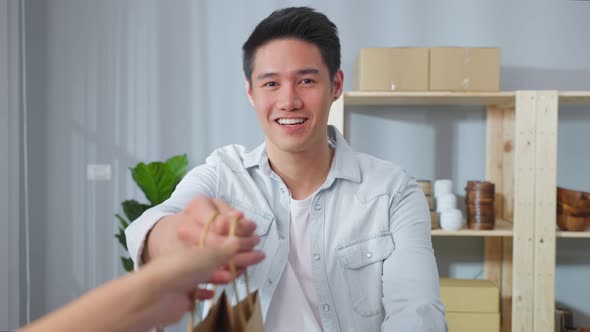 Portrait of Asian young businessman handing product order to customer.