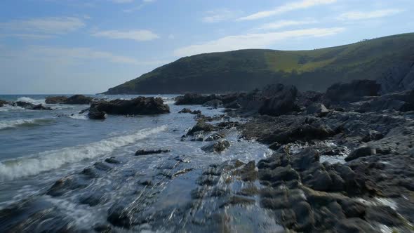 Slow Flight Over the Rugged Coastline with a Hilly Landscape