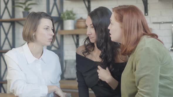 Young Caucasian Woman Sharing Secrets with Friends Indoors