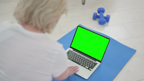 Rear View of Senior Old Woman Using Laptop with Chroma Key Screen on Yoga Mat