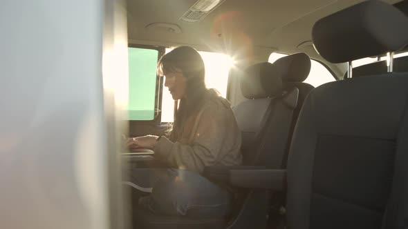 Traveling woman working on laptop in van