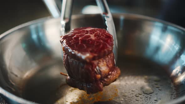 Close-up of a filet mignon being cooked in a frying pan