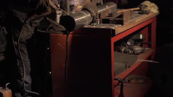 Welder welding stainless steel pipe together using shielded metal arc welding. TILT UP MEDIUM SHOT