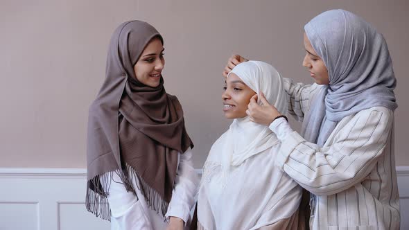 Three Muslim Girls Talk Together Getting Ready Smiling in Beige Studio