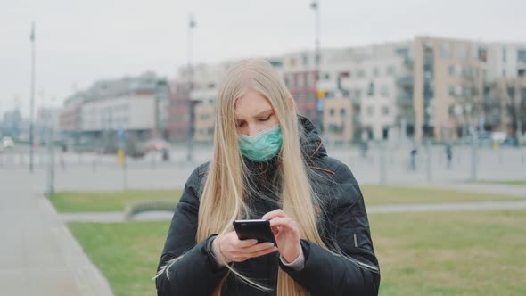 Young Female Wearing Medical Mask Reading Outbreaking News About Coronavirus Disease on the Street