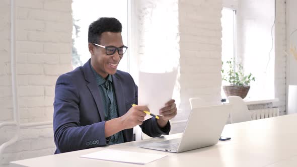 Businessman Celebrating Success While Reading Documents in Office