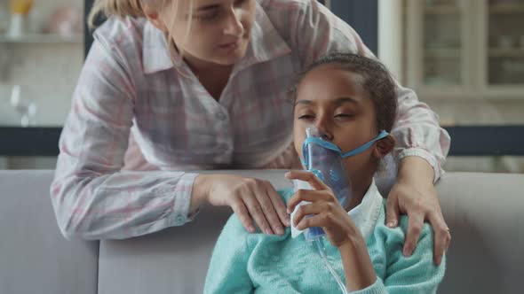 Caring Mom Supports Unwell Child in Nebulizer Mask