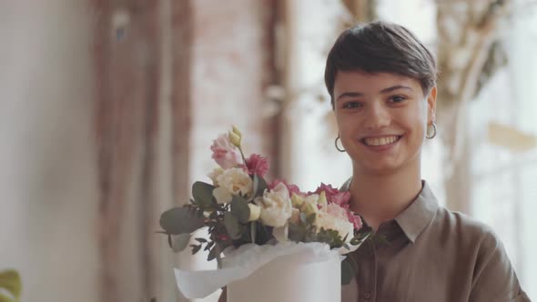 Happy Young Female Florist Holding Flower Composition and Smiling at Camera