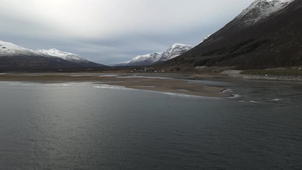 Flying Over Calm Waters Of Fjord With Snowy Mountains In Breivikeidet, Northern Norway. - aerial