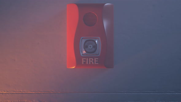 Close up shot of flashing strobe red fire alarm during fire in the room.