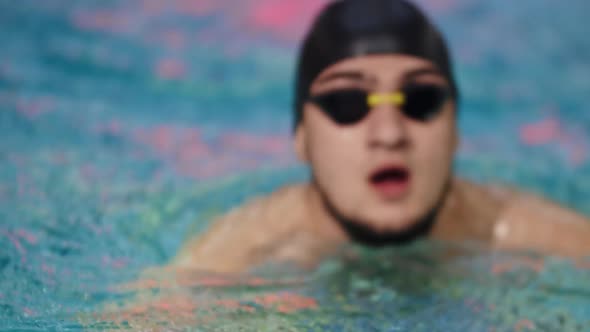 Young Bearded Man Swimmer Comes Up From the Water and Takes the Glasses Off His Face