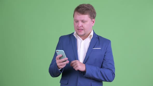 Happy Overweight Bearded Businessman Talking While Using Phone