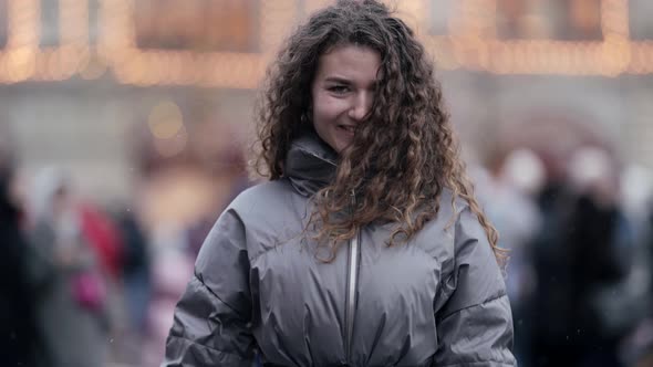 Happy Young Woman Is Strolling on Large Square of Big City at Winter Smiling Broadly and Laughing To