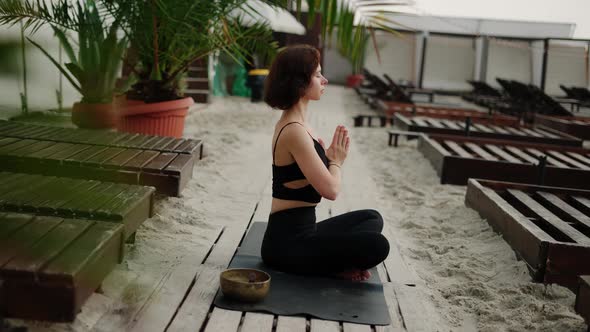 Woman Sits in Meditation on the Beach