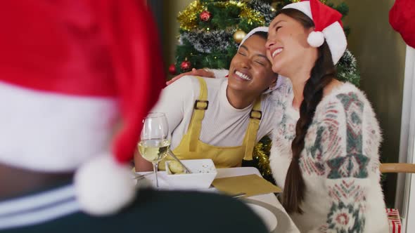 Two diverse female friends celebrating meal with friends at christmas time