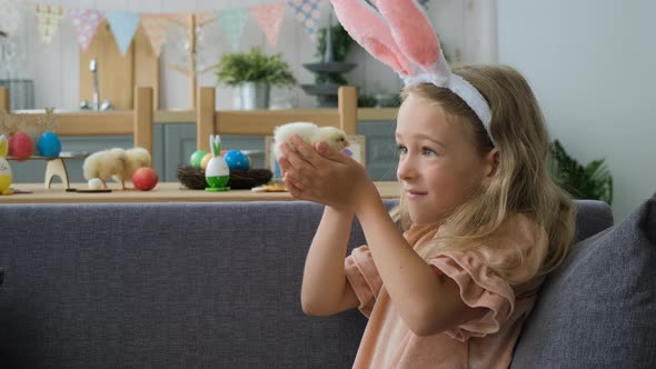 Girl in Bunny Ears Playing with Chick in Kitchen