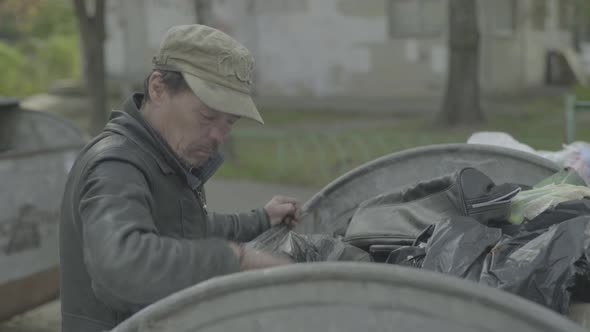 A Beggar Homeless Man Tramp Is Looking for Food in a Trash Can. Kyiv. Ukraine