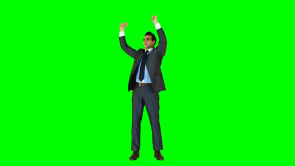 Businessman standing with arms up against green background