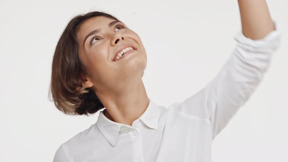 Young Beautiful Brunette East Asian Female in Shirt Looking Up Smiling in Astonishment on White