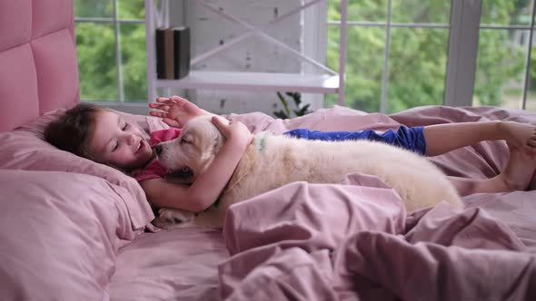 Sweet Little Girl Talking To Puppy Lying on Bed