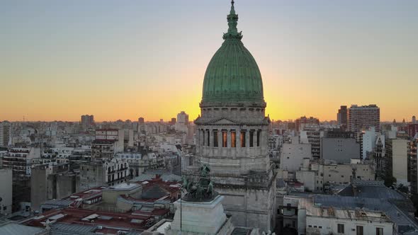 Aerial dolly out of Argentine Congress building with green bronze dome at sunset in Balvanera neighb