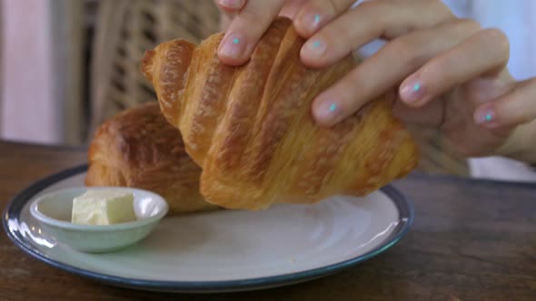 Close Up of Hands Breaking in Half Freshly Baked Crusty Flaky Buttery Croissant