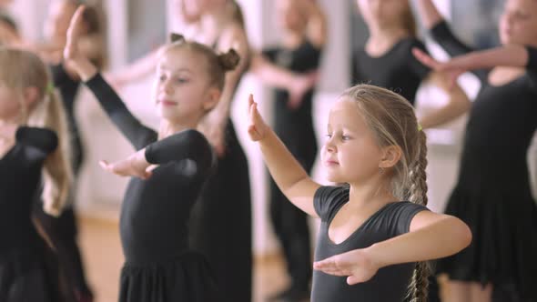 Portrait of Pretty Little Girl Standing in Fourth Ballet Position with Other Children in Dance