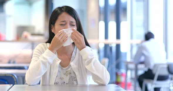 Woman suffer from flu and sneeze inside  restaurant