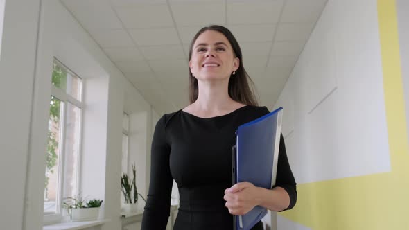 Happy Woman Teacher Walking Down School Corridor Looking Forward